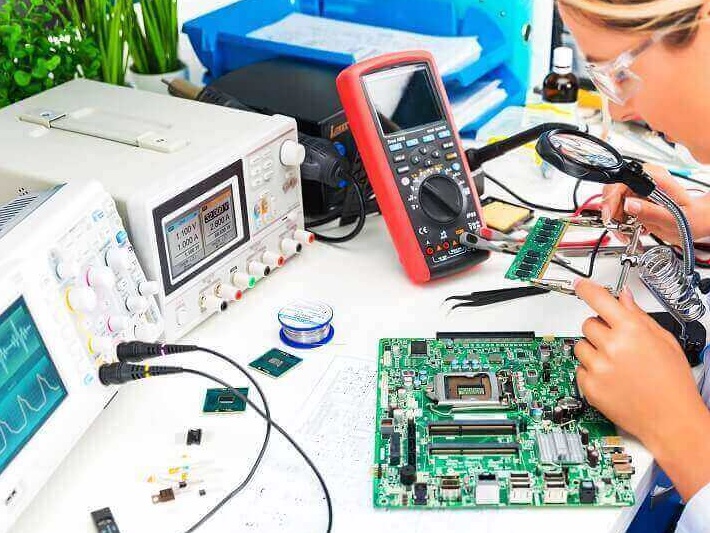 Electronics bench with bench power supply, multimeter, oscilloscope and a PCB under rework